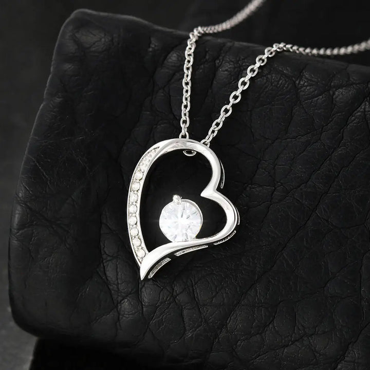Silver heart-shaped pendant necklace on a dark textured surface