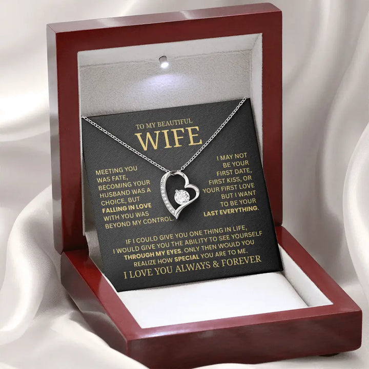 Heart-shaped necklace in a wooden box with a sentimental message card on a white fabric background