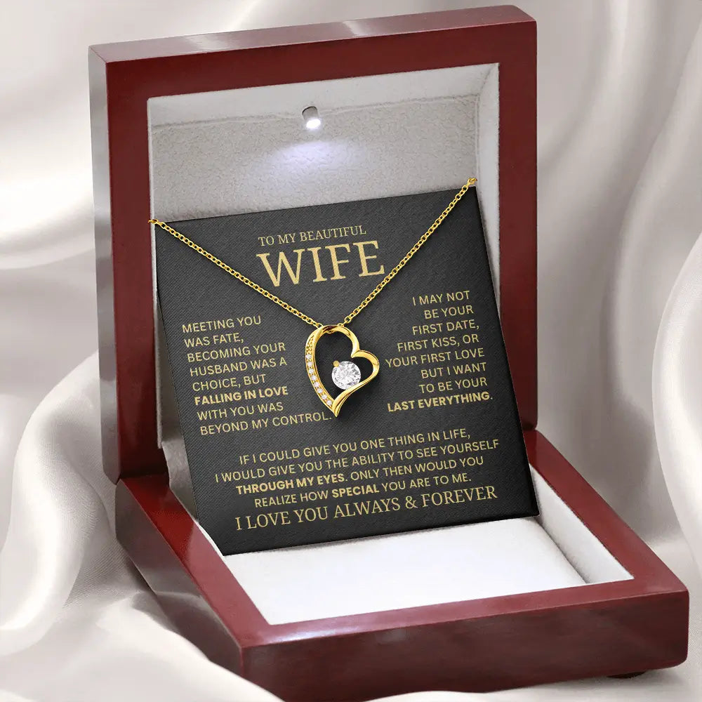 Heart-shaped necklace in a wooden box with a sentimental message card on a white fabric background